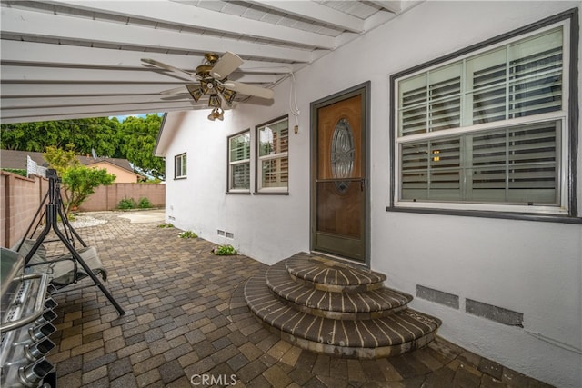 doorway to property with crawl space, stucco siding, fence, and a ceiling fan