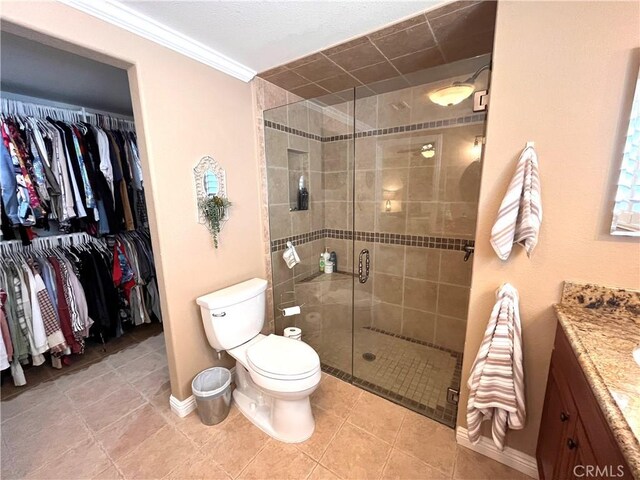 full bathroom featuring vanity, toilet, a stall shower, baseboards, and ornamental molding