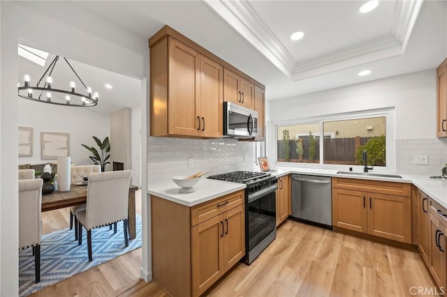 4592 Paloma Ln, Yorba Linda, CA 92886 - kitchen featuring appliances with stainless steel finishes, a sink, a raised ceiling, light wood-style floors, and a chandelier