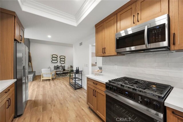 4592 Paloma Ln, Yorba Linda, CA 92886 - kitchen featuring stainless steel appliances, a raised ceiling, brown cabinetry, light wood-type flooring, and light countertops
