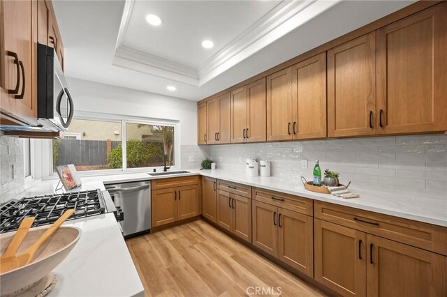 4592 Paloma Ln, Yorba Linda, CA 92886 - kitchen featuring stainless steel appliances, a sink, a tray ceiling, brown cabinetry, and light countertops