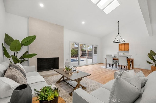 4592 Paloma Ln, Yorba Linda, CA 92886 - living room featuring high vaulted ceiling, a chandelier, a fireplace, light wood finished floors, and a skylight