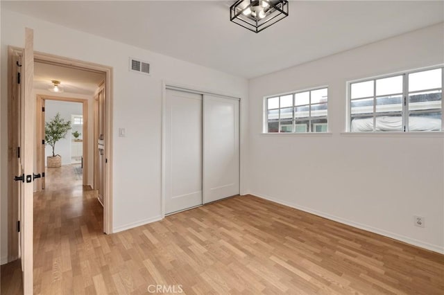 unfurnished bedroom with light wood-style floors, baseboards, and a closet