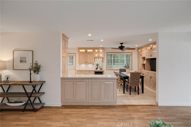 kitchen featuring light wood-style flooring, a peninsula, recessed lighting, glass insert cabinets, and light countertops