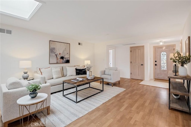 living room featuring light wood-style flooring and a skylight