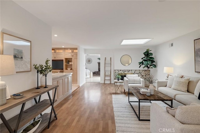 living room with light wood-style flooring, a skylight, recessed lighting, and baseboards