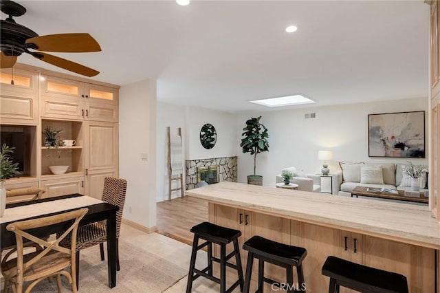 kitchen with a kitchen bar, recessed lighting, ceiling fan, open floor plan, and light stone countertops