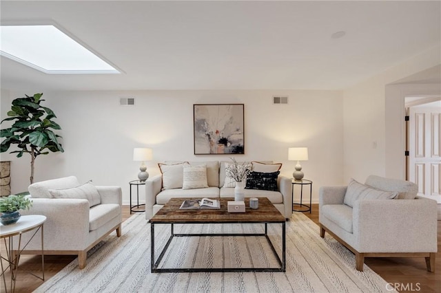 living area featuring a skylight, light wood-style flooring, and baseboards