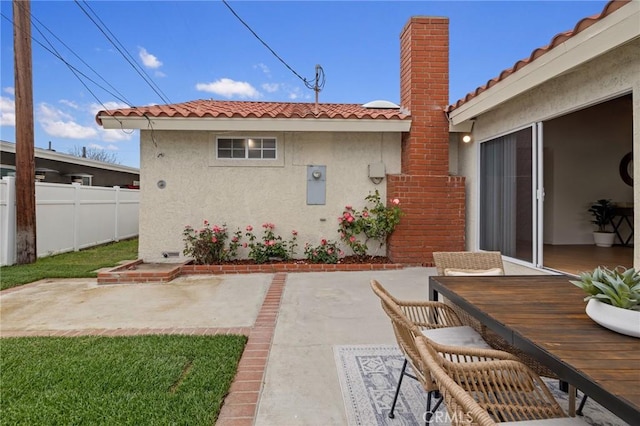 rear view of house with a patio area, stucco siding, fence, a chimney, and a tile roof