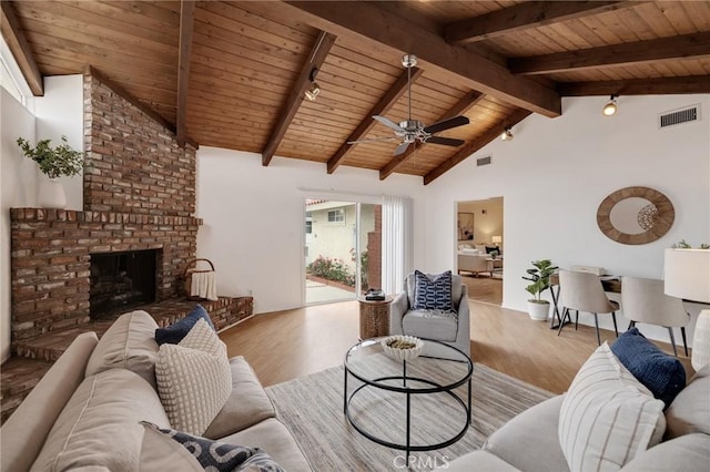living room featuring wood ceiling, wood finished floors, track lighting, a fireplace, and a ceiling fan