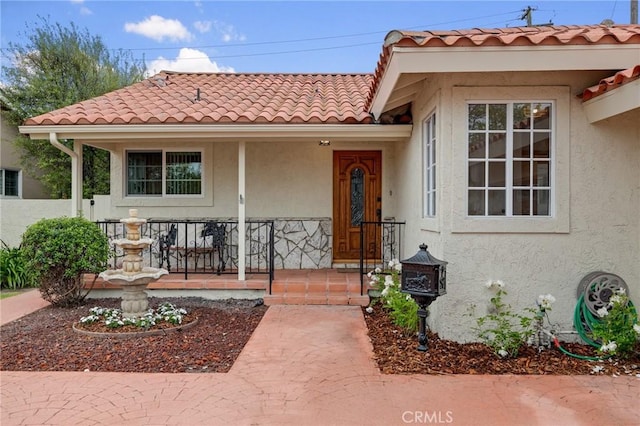view of front of house featuring stucco siding, a tiled roof, and a porch