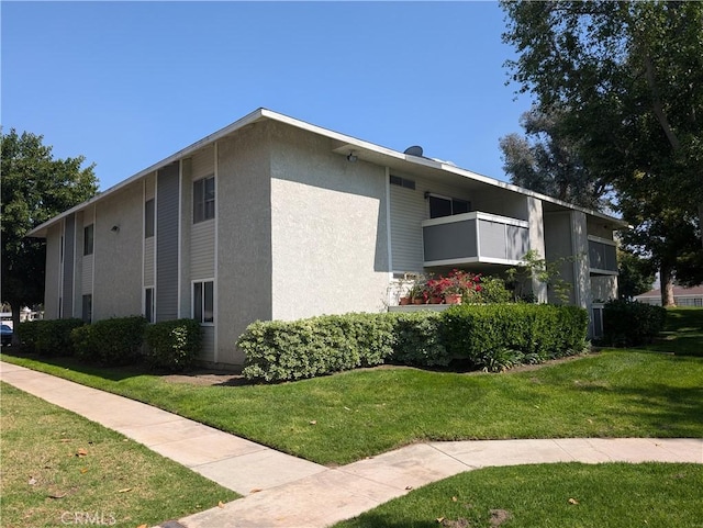 view of home's exterior featuring a yard, stucco siding, and a balcony