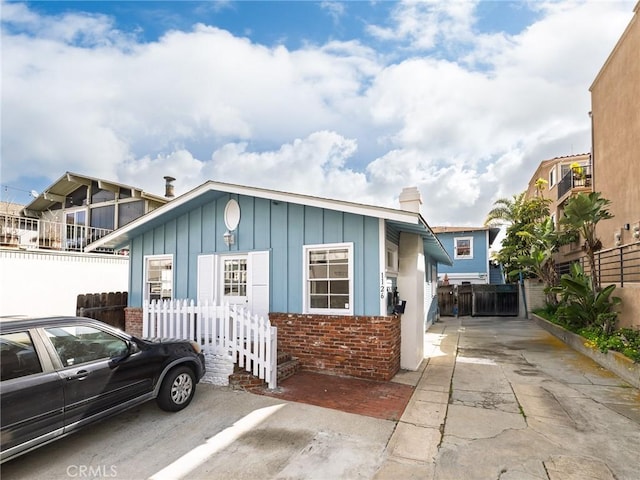 1122 Loma Dr, Hermosa Beach, CA 90254 - view of front of house with board and batten siding, brick siding, a chimney, and fence