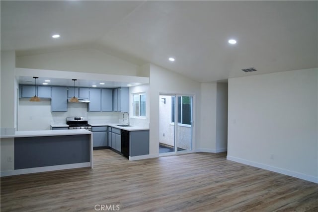 kitchen with gas stove, vaulted ceiling, a sink, open floor plan, and light countertops