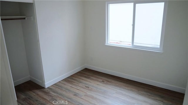 unfurnished bedroom featuring baseboards, light wood-type flooring, and a closet