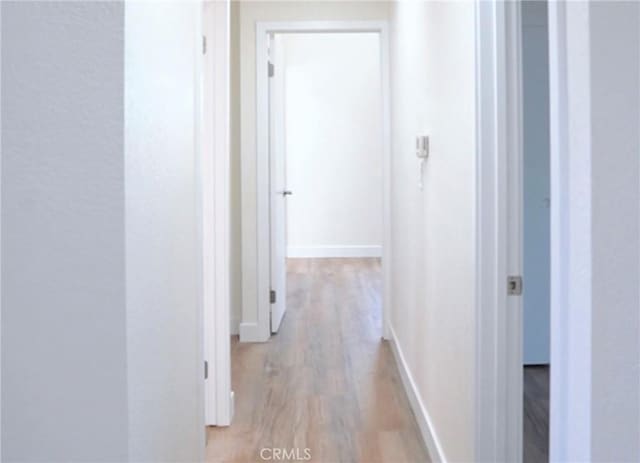 hall with light wood-type flooring and baseboards