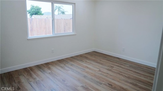 unfurnished room with plenty of natural light, baseboards, and wood finished floors