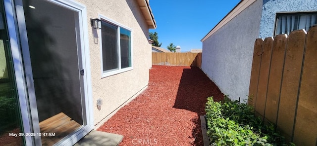 view of side of home with fence and stucco siding