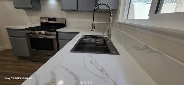 27798 Cloud Dance Ct, Menifee, CA 92585 - kitchen featuring stainless steel range with gas cooktop, gray cabinetry, dark wood-style floors, light stone counters, and a sink