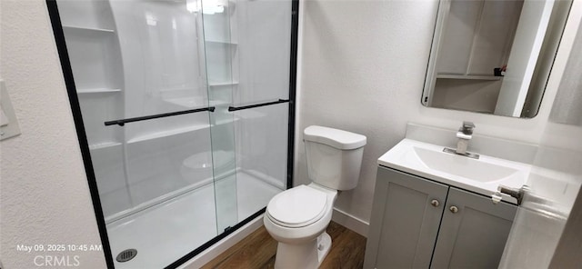 full bath with toilet, a stall shower, wood finished floors, vanity, and a textured wall