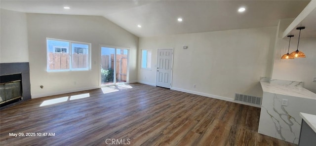unfurnished living room with dark wood-style flooring, lofted ceiling, a glass covered fireplace, recessed lighting, and baseboards