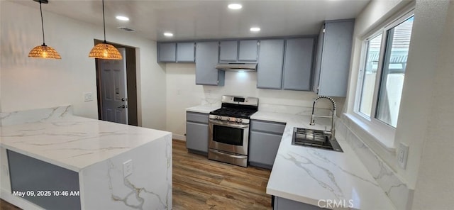 kitchen featuring stainless steel range with gas stovetop, gray cabinets, a sink, light wood-style floors, and recessed lighting