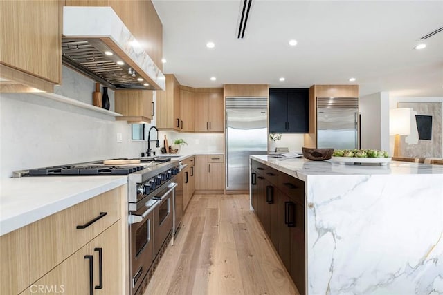 18101 Green Meadow Dr, Encino, CA 91316 - kitchen with high end appliances, wall chimney range hood, light brown cabinets, modern cabinets, and a large island