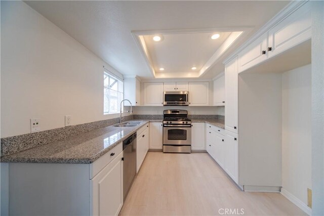 kitchen with appliances with stainless steel finishes, a sink, dark stone countertops, white cabinetry, and recessed lighting