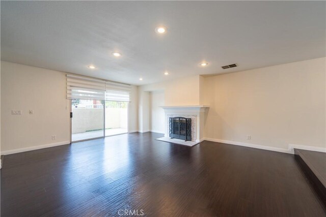 unfurnished living room with a fireplace with flush hearth, baseboards, dark wood-type flooring, and recessed lighting