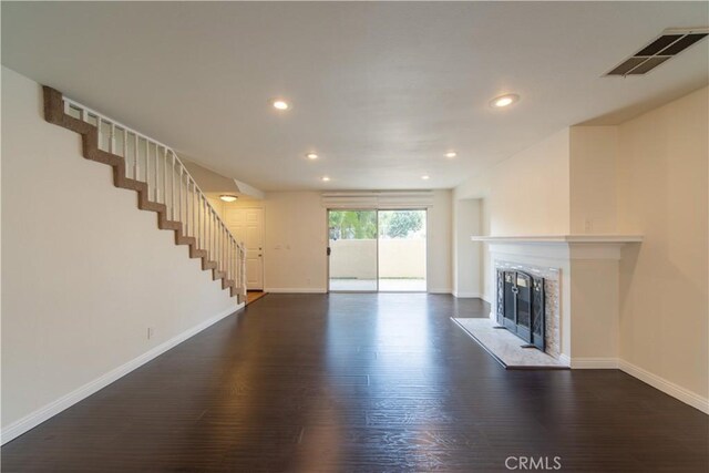 unfurnished living room featuring dark wood-style flooring, baseboards, stairs, a fireplace, and recessed lighting
