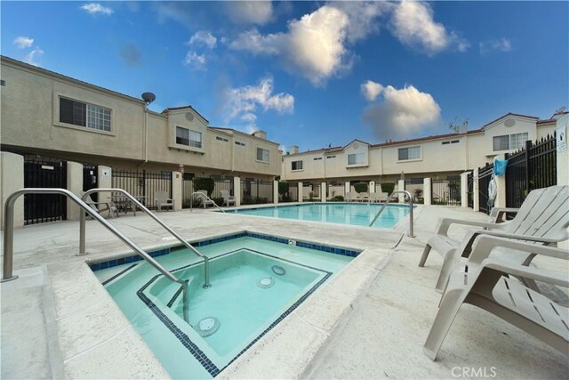 community pool with a community hot tub, fence, and a patio