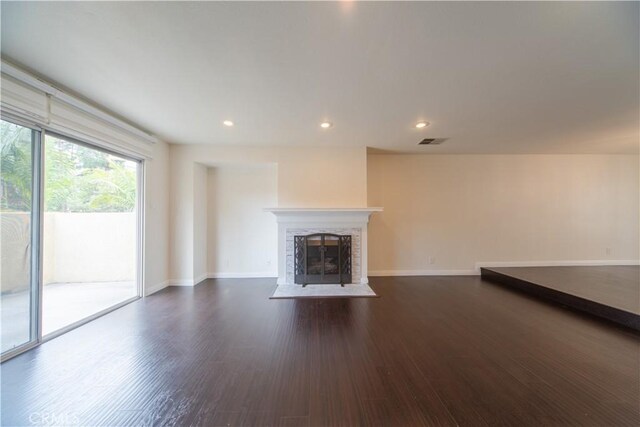 unfurnished living room with dark wood-style flooring, baseboards, a premium fireplace, and recessed lighting