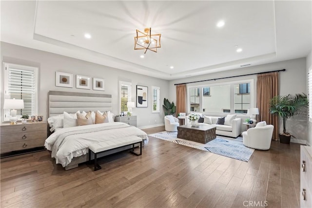 bedroom with a tray ceiling, a chandelier, wood finished floors, baseboards, and recessed lighting