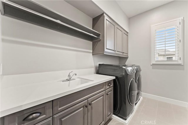 washroom featuring washing machine and dryer, cabinet space, baseboards, and light tile patterned floors