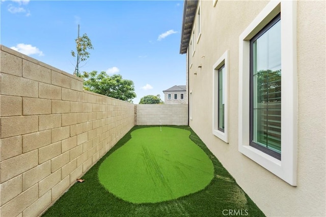 fenced backyard with a putting green