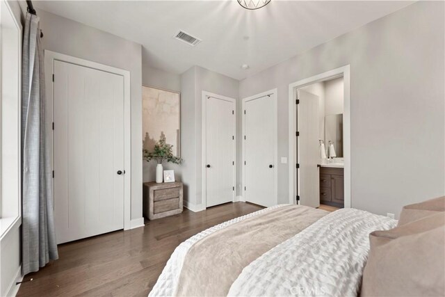 bedroom featuring multiple closets, wood finished floors, connected bathroom, and baseboards