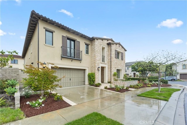 mediterranean / spanish house with a balcony, concrete driveway, stucco siding, a garage, and stone siding