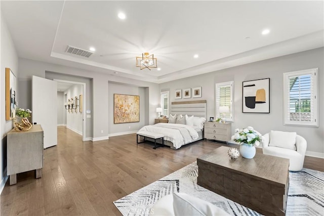 bedroom with a raised ceiling, a chandelier, wood finished floors, baseboards, and recessed lighting