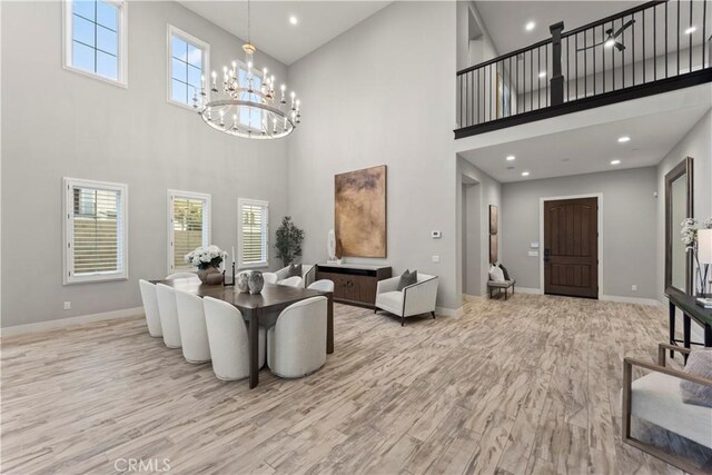 living area with a high ceiling, a chandelier, baseboards, recessed lighting, and wood finished floors