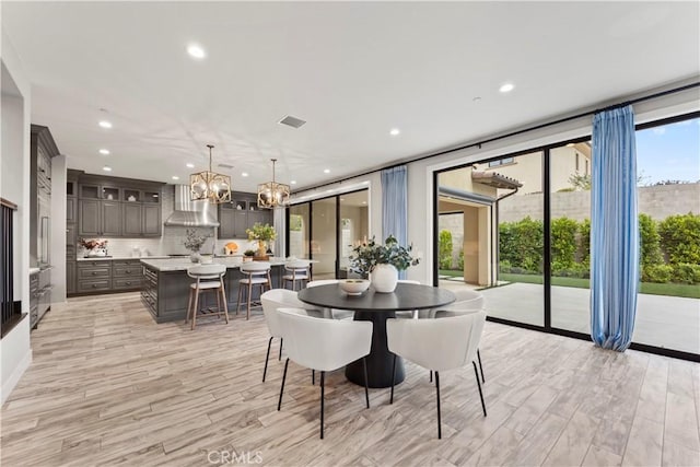 dining area with light wood-style flooring, a chandelier, recessed lighting, and expansive windows