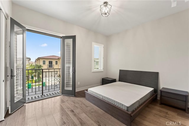 bedroom with access to outside, wood finished floors, and baseboards