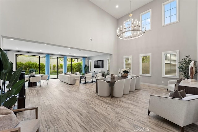 living room with a towering ceiling, a chandelier, plenty of natural light, recessed lighting, and baseboards