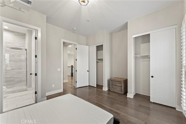 bedroom featuring multiple closets, dark wood-type flooring, and baseboards