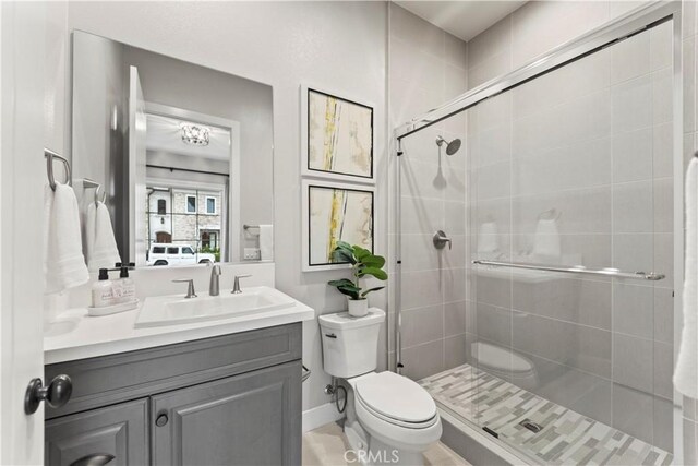 bathroom featuring a shower stall, toilet, vanity, and baseboards