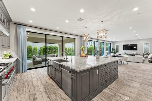 kitchen featuring stainless steel dishwasher, a sink, gray cabinets, recessed lighting, and light wood-type flooring