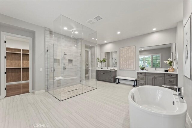 bathroom with a stall shower, recessed lighting, vanity, a freestanding tub, and baseboards