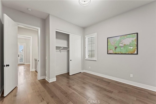 unfurnished bedroom with wood finished floors, a closet, and baseboards