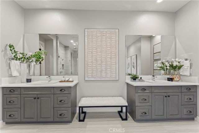 full bathroom featuring two vanities, a stall shower, and baseboards