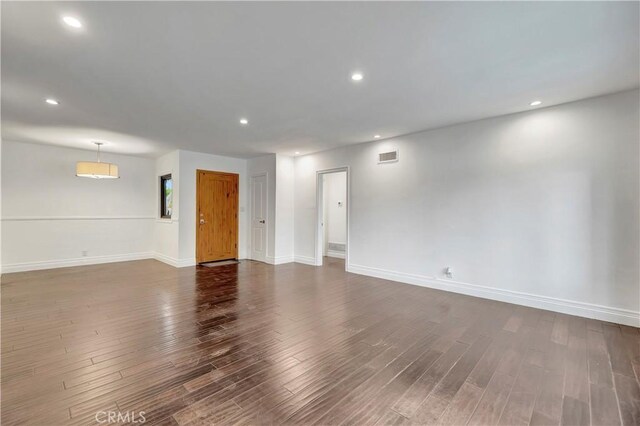 empty room with dark wood-style flooring, baseboards, and recessed lighting