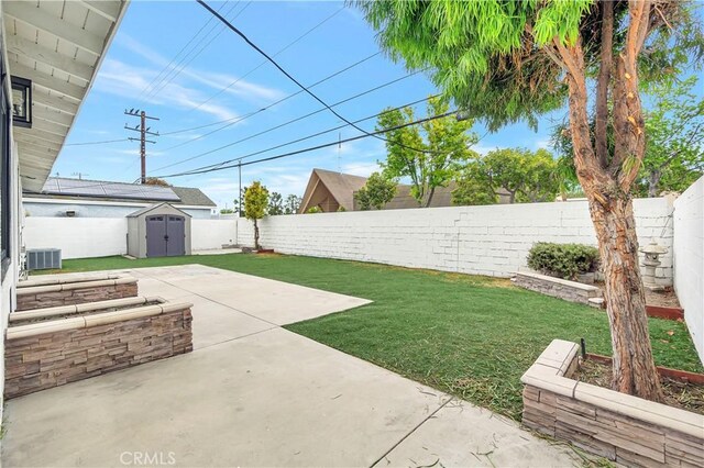 view of yard featuring a storage unit, a patio, an outbuilding, and central AC